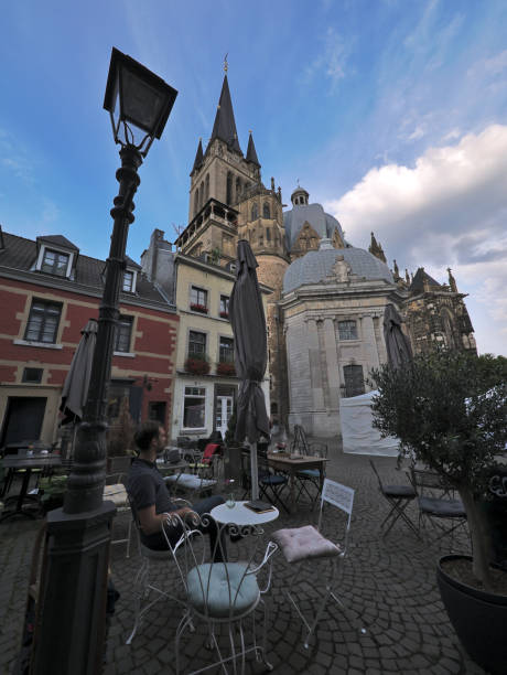 istock Young man sitting in cafe in front of Aachen cathedral 1029047092