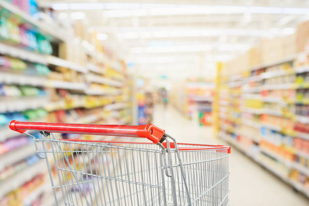 istock Supermarket aisle blurred background with empty red shopping cart 1029062270