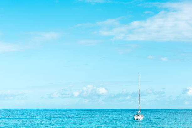 Big open blue day with a single boat floating quietly. Calm waters with a clear sky.