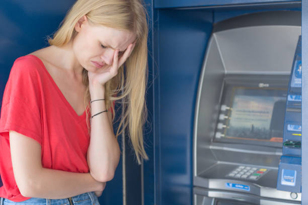 Sad woman standing in front of a ATM bank machine. No money. Distraught young girl is visibly upset in front of the ATM. Her balance is allot lower then it should be. money cry stock pictures, royalty-free photos & images
