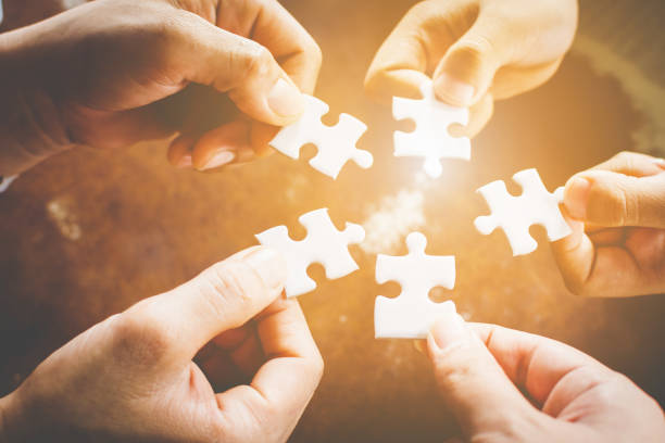 hand of diverse people connecting jigsaw puzzle. concept of partnership and teamwork in business - harmony imagens e fotografias de stock