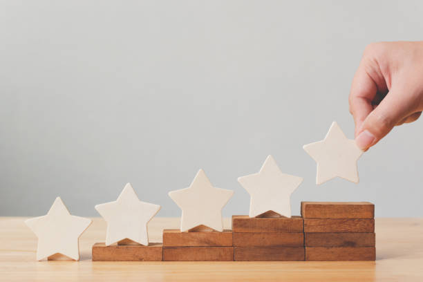 рука положить деревянные пять звезд формы на столе. лучшие отличные бизнес-услуги рейтинг клиент опыт концепции - perfection стоковые фото и изображения