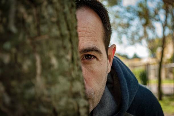 istock Portrait of man behind a tree looking at the camera 1029082012