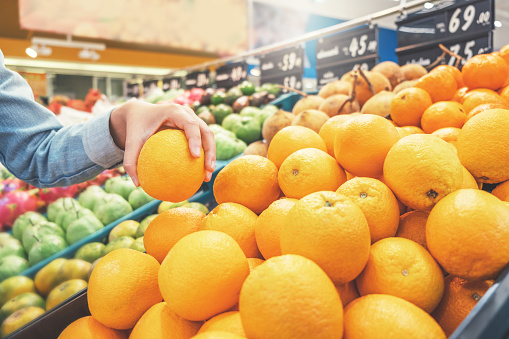 Asian women shopping Orange Fruit and Healthy food vegetables in supermarket