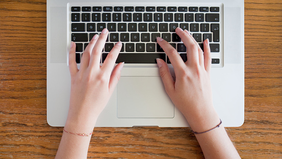 closeup of young female hands typing on laptop