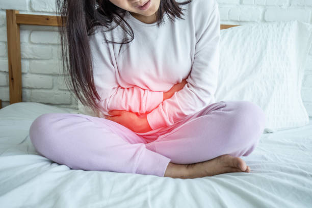 mulher ter dor na bexiga, sentado na cama no quarto após o despertar do sentimento tão doente e doloroso, conceito de saúde - have - fotografias e filmes do acervo