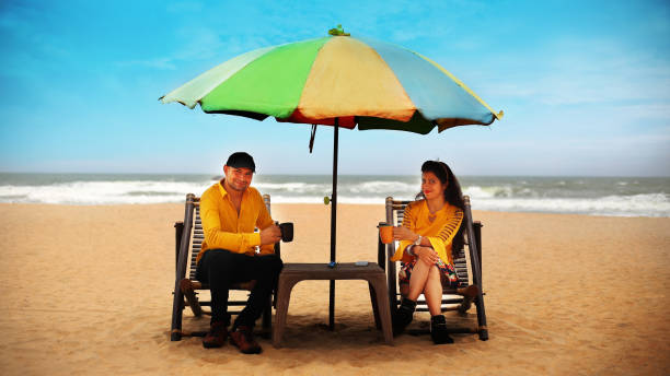 Couple enjoying hot coffee on tropical sandy beach