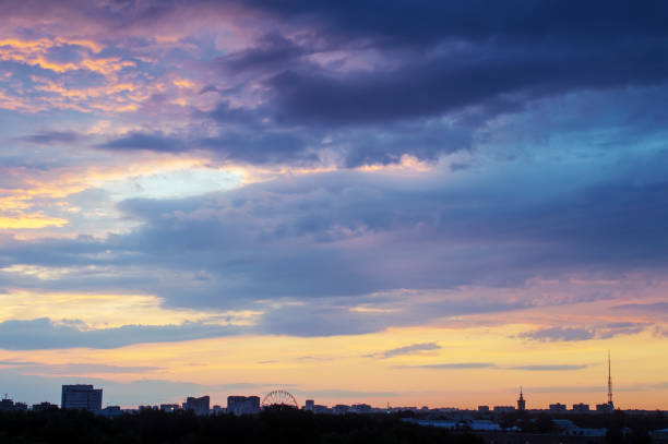 blue and orange clouds at sunset over the city stock photo