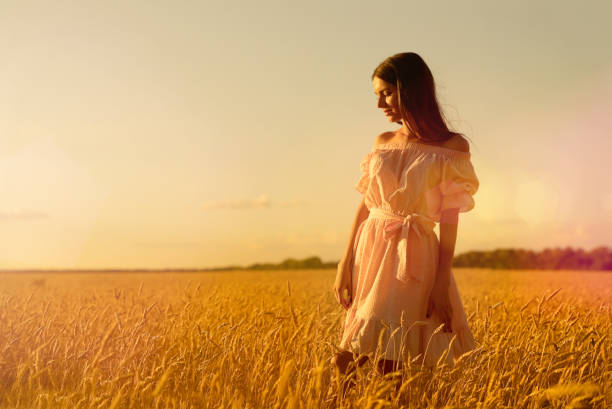 Woman in wheat field at sunset
