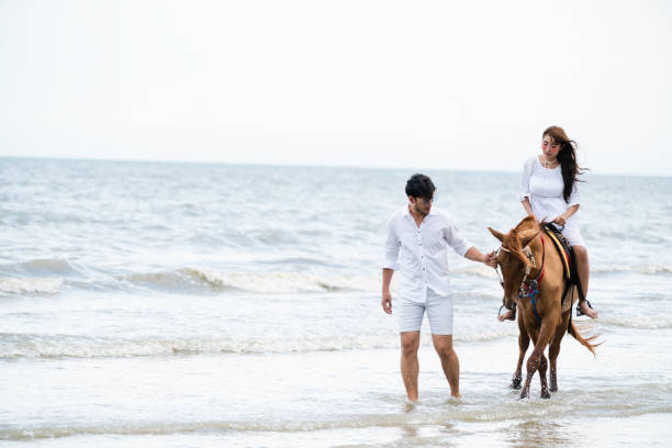 istock Young couple goes horse riding on tropical beach. 1029172848