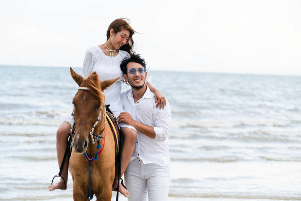 istock Young couple goes horse riding on tropical beach. 1029172882