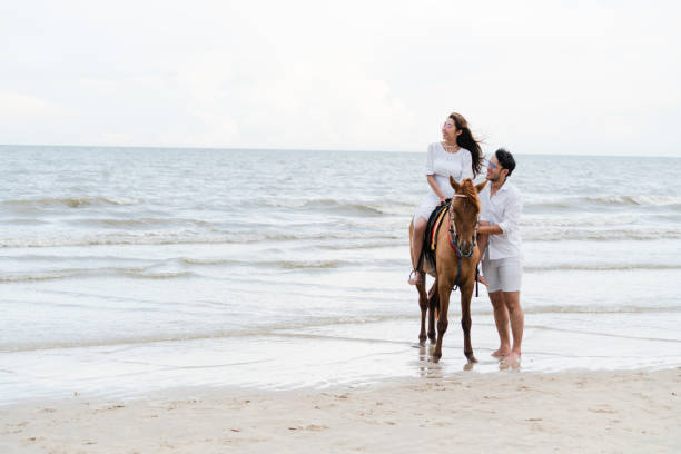 istock Young couple goes horse riding on tropical beach. 1029172942