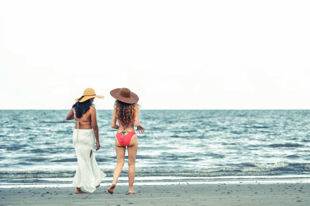 istock Happy women go sunbathing at sand beach in summer. 1029173580