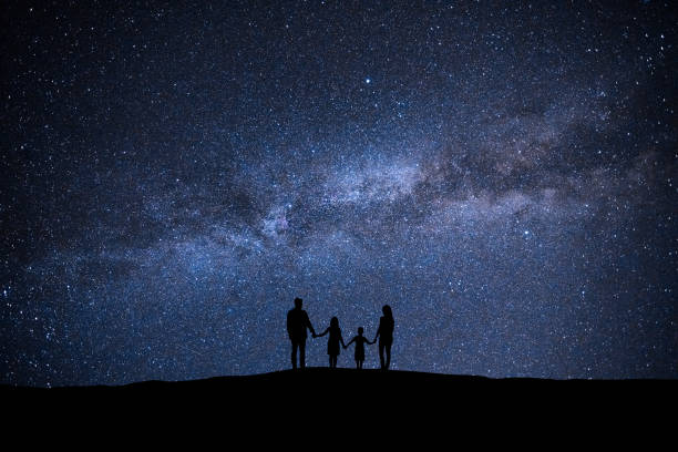 The family standing on the picturesque starry sky background stock photo
