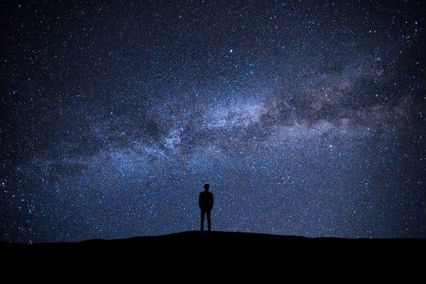 el hombre de pie en el fondo de cielo estrellado pintoresco - lluvia de meteoritos fotografías e imágenes de stock