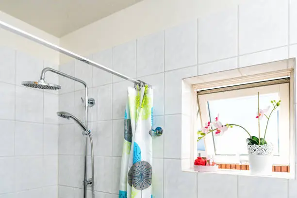 Modern tiles, tiled bathroom, shower, heads, tension rod with rings, colorful curtain, opened window, sunny, bright sunlight, light and potted orchid flower plant in pot