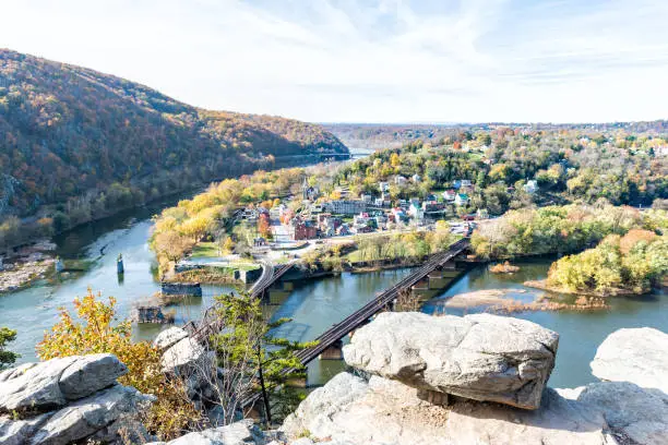 Harper's Ferry overlook with colorful orange yellow foliage during fall, autumn forest with small village town by river in West Virginia, WV