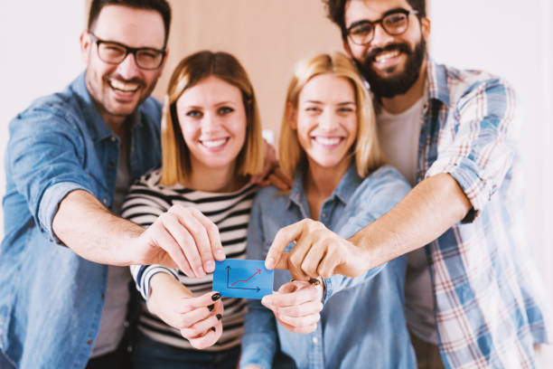 istock Group of young smiling designers holding together a blue note sticker . 1029191814