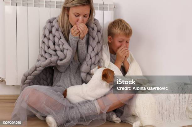 Cold Home Freezing Family Mother And Son Wrapped In Blanket Sitting Near Heater Stock Photo - Download Image Now