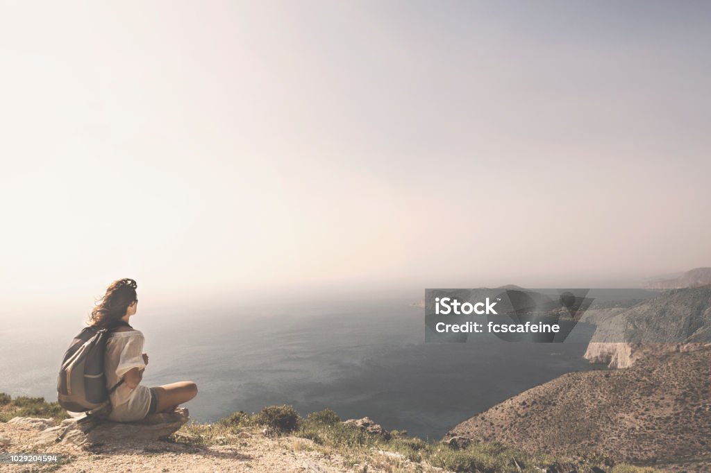 traveling woman relaxes and meditates on the peak of a mountain Yoga Stock Photo