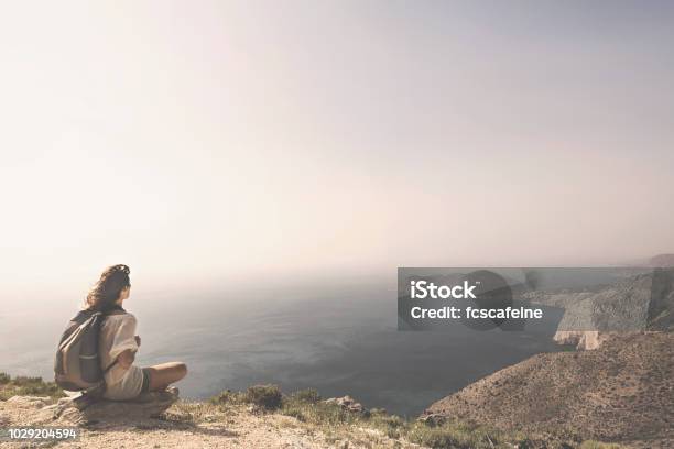 Traveling Woman Relaxes And Meditates On The Peak Of A Mountain Stock Photo - Download Image Now