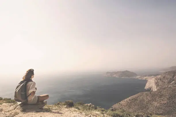 Photo of traveling woman relaxes and meditates on the peak of a mountain