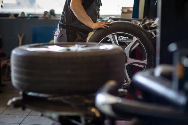 Wheel balancing or repair and change car tire at auto service garage or workshop by mechanic