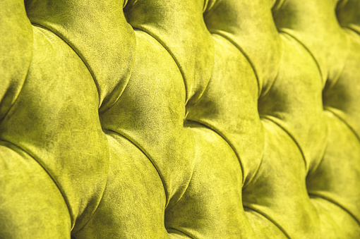 Velor surface of sofa close-up. Training equipment-velor mats tightened with buttons. Yellow chesterfield style quilted upholstery background close up.