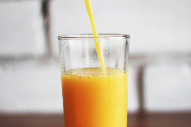 istock freshly squeezed orange juice pours into glass on brick wall background in loft style 1029224444