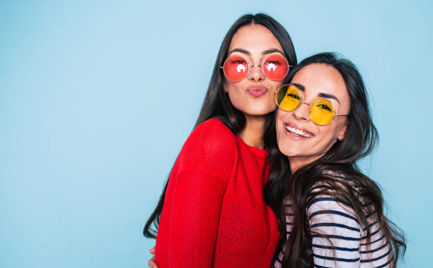 freunde für immer. zwei süße schöne freundinnen in sonnenbrille posiert mit lächeln auf blauem hintergrund - freundin fotos stock-fotos und bilder
