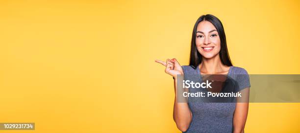 Photo Of Young Excited Beautiful Happy Brunette Woman Girl Pointing Away And Smile Isolated On Yellow Background Banner Stock Photo - Download Image Now