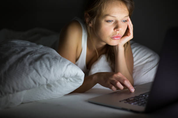 istock Pretty, young woman using her laptop computer in bed 1029243070