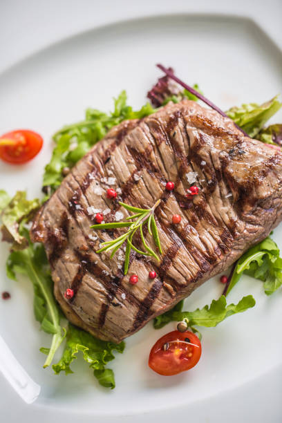 close-up teil saftige flanke steak vom salat salz pfeffer und rosmarin auf weißen teller. - skirt steak steak close up grilled stock-fotos und bilder