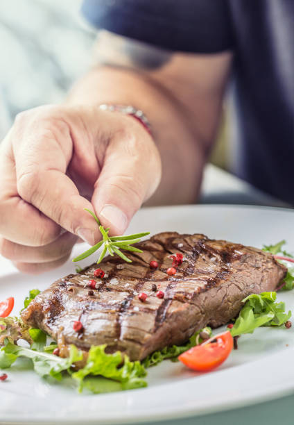 istock Chef in hotel or restaurant kitchen cooking only hands. Prepared beef flank steak with vegetable decoration. 1029246238