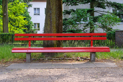 Red park bench at a street corner in Berlin-Zehlendorf, Germany.