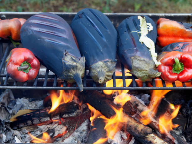 Roasting eggplants and red peppers over a campfire