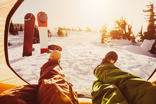 Two friends snowboarders are relaxing in tent against sunset. Ski resort concept