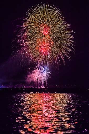 Fireworks over the harbor with glowing reflection in the water