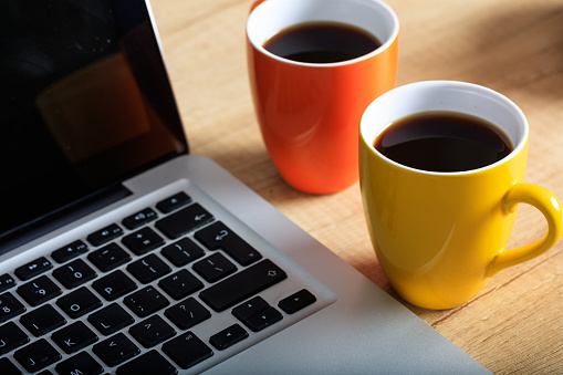 Cups of coffee and a laptop on an office table