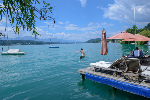 Portschach, Austria - 1 July 2018: Sunchairs on wooden pier and view of beautiful alpine lake Worthersee on Austria