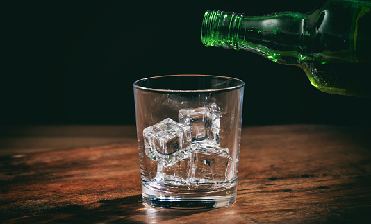 Glass with ice cubes on wooden background
