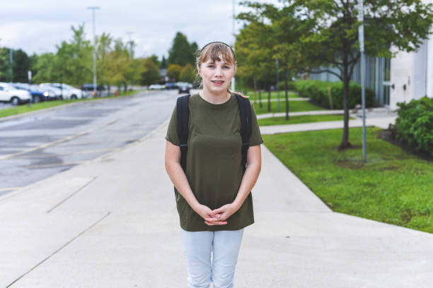 adolescente heureuse debout sur le trottoir qui longe le front d’une école. - let down photos et images de collection