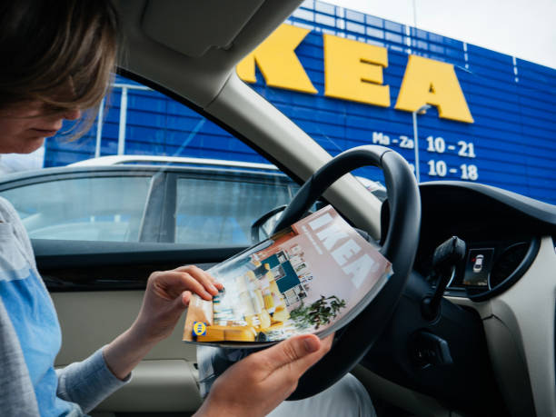 donna che legge il catalogo ikea all'interno dell'auto nel parcheggio ikea - editorial concepts and ideas retail place store foto e immagini stock