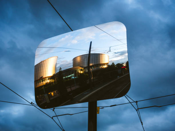 Street mirror reflecting modern building in sunlight Strasbourg: Reflection in street mirror of European Court of human rights under cloudy dark sky european court of human rights stock pictures, royalty-free photos & images