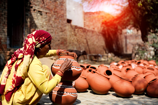 Indian women painting mud pot in traditional style.