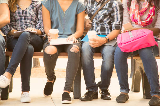 istock College student friends sitting on university campus bench. 1029308392