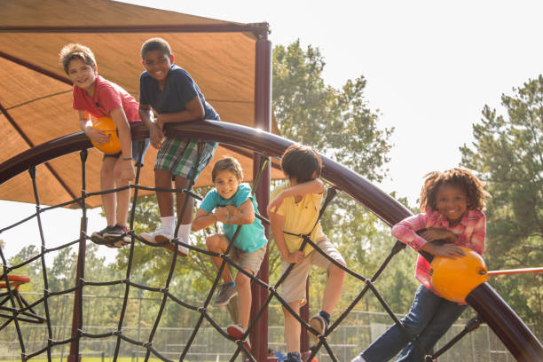 wieloetniczna grupa uczniów bawiących się na szkolnym placu zabaw. - child jungle gym playground laughing zdjęcia i obrazy z banku zdjęć