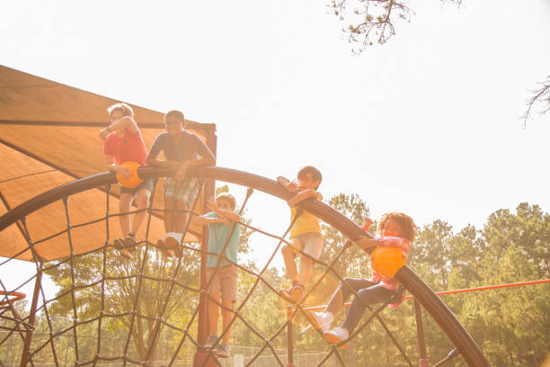 multi-ethnic group of school children playing on school playground. - child jungle gym playground laughing imagens e fotografias de stock