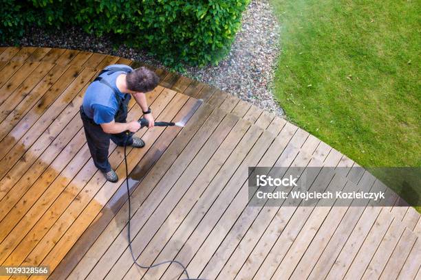 Man Cleaning Terrace With A Power Washer High Water Pressure Cleaner On Wooden Terrace Surface Stock Photo - Download Image Now