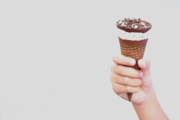 istock Hand holding vanilla ice cream with chocolate on top in waffle cone on white background 1029329594